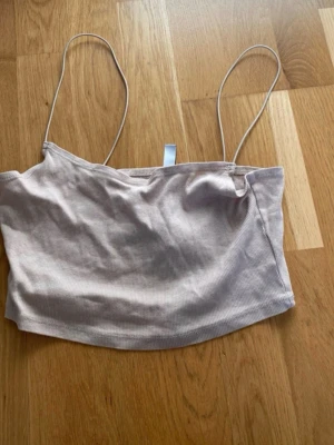 Beige ribbad linnetopp med smala band - Snygg beige ribbad linnetopp från Boohoo med smala axelband och croppad passform. Perfekt till jeans eller kjol för en avslappnad och trendig look. Tunt och mjukt material som känns skönt mot huden.