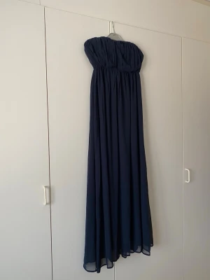 Marinblå chiffongklänning - Perfekt till bal eller annan fin tillställning. Silikon på insidan så den håller sig uppe, axelband medföljer om man vill sätta dit. Helt ny är den, mäter vid intresse! Djur och rökfritt hem. Storlek 34/XS