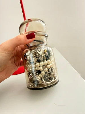 Mystery jewlery jar  - Säljer en fin glasburk fylld med olika smycken, bland annat ringar, halsband, öronhängen och midjeband. Smyckena är i olika former och material, silver, guld och pärlor.  Perfekt för dig som gillar att mixa och matcha accessoarer.