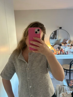 Grå stickad kortärmad kofta - Mysig grå stickad kofta med korta ärmar och knappar framtill. 