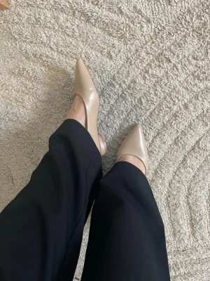 Beige ballerinaskor med spetsig tå - Snygga beige ballerinaskor med spetsig tå och låg klack. Skorna är tillverkade i ett slätt material som ger en stilren look. Perfekta för dig som gillar minimalistisk och elegant stil. Passar till både jeans och dressade outfits.