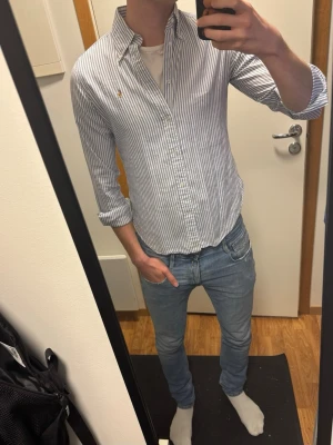 Ralph Lauren skjorta vit, ljusblå randig - Utmärkt skick, inga defekter Stl 12 motsvarar storlek S Längd 66cm, bredd 50cm  Skriv vid funderingar Kolla in profilen för fler liknande plagg!