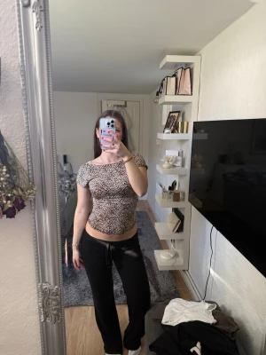 Leopardmönstrad tight topp - Snygg leopardmönstrad topp med kort ärm och figurnära passform. T-shirten har rund halsringning och är i stretchigt material som sitter skönt på kroppen. Perfekt för dig som gillar trendiga mönster och vill sticka ut lite extra.