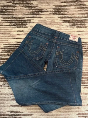 Vintage True Religion jeans mörkblå - Snygga mörkblåa jeans från True Religion, i storlek 27 motsvarande S. Midjemått: 38 cm. Innerbenslängd: 77 cm. Low waist och utsvängda 