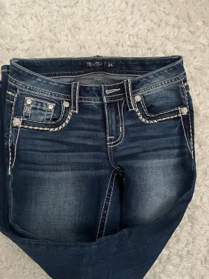 Mörkblå Miss Me jeans med kontrastsömmar - Snygga mörkblå jeans från Miss Me med tydliga kontrastsömmar och dekorativa fickor fram och bak. Jeansen har en klassisk femficksdesign. Dom är nästan helt oanvända.