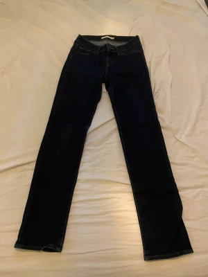 Mörkblå jeans från Levis  - Snygga mörkblå jeans från Levis med klassisk rak passform och femficksdesign. Jeansen har normal midja och är tillverkade i ett stretchigt denimtyg som sitter bekvämt hela dagen. Perfekta för en avslappnad och stilren look.