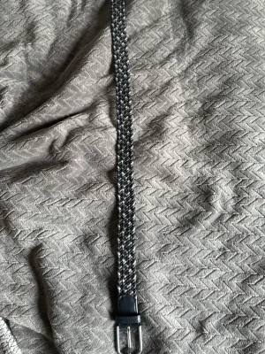 Blå grått flätat bälte från One wear 90 cm - Blå gråt flätat bälte från one wear i 90 cm med ett silver späne.