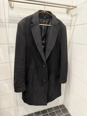 Rock Herr Ull - Svart ull rock herr  Sparsamt använd och i fint skick Avtagbar väst krage  Storlek: 52 Märke: Stones Material: 70% wool 20% polyamid 10% cashmere