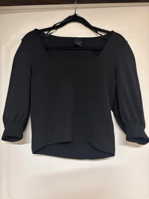 Svart topp med puffärm  - Trendig svart topp från Only med fyrkantig ringning och puffiga trekvartsärmar. Tillverkad i ett mjukt, stretchigt material som ger en snygg passform. Perfekt att styla med både jeans och kjol.