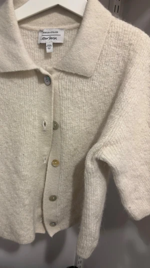 Krämvit kofta från & Other Stories - Mysig krämvit kofta från & Other Stories med klassisk krage och knappar i olika färger. Koftan har en rak, boxig passform och är stickad i ett mjukt material som känns lyxigt. Perfekt för lager på lager och enkel att styla till olika looks.