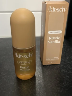 Kitsch Rustic Vanilla hårparfym - Kitsch Rustic Vanilla hårparfym i en stilren, matt beige och brun glasflaska med rundad kork. Doften har inslag av vanilj, tonkaböna och ceder. Flaskan rymmer 50 ml och kommer i matchande förpackning. Perfekt för dig som vill fräscha upp håret med en varm, söt doft.