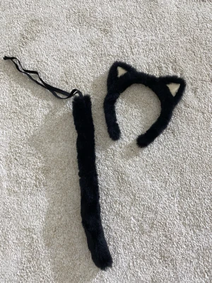 Halloween katt öron och svans - Säljer dessa halloween prylar som är en svart svans som man kan knäppa runt midjan och ett par matchande katt öron. 