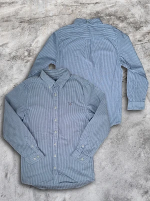 Skjorta från Gant - Säljer en snygg randig skjorta från Gant. Skjortan är i vitt och ljusblått med randigt mönster, helt felfri och i storleken 134-140 cm. Skriv gärna om ni har fler frågor eller vill ha mer bilder och för ytterligare ursnygga plagg (i större storlekar) checka in våran profil🤙