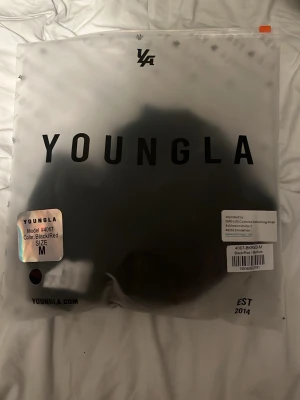 Svart/röd t-shirt från YoungLA - Säljer en svart och röd t-shirt från YoungLA, modell 4067. T-shirten har en modern och sportig look, perfekt för dig som gillar streetwear. Materialet är mjukt och bekvämt, och passformen är normal. Snygg logga på bröstet för extra stilpoäng.