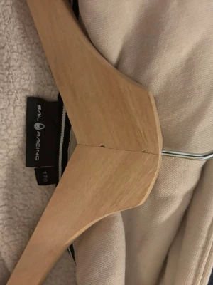 Beige hoodie från Sail Racing - Snygg beige hoodie från Sail Racing med broderad logga på huvan. Tillverkad i mjukt material som känns skönt mot huden. Klassisk passform med huva och långa ärmar.