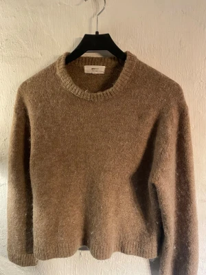 Beige stickad tröja från Gina Tricot - Mysig beige stickad tröja från Gina Tricot i ullblandning. Tröjan har rund halsringning, långa ärmar och ribbade muddar vid ärmslut och nederkant. Perfekt för lager på lager och en avslappnad look. Använt 2-3ggr.