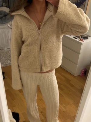 Beige teddyjacka med dragkedja - Mysig beige teddyjacka med hög krage och dragkedja framtill. 