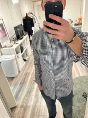 Blårutig skjorta från Ralph Lauren - Säljer en klassisk blårutig skjorta från Ralph Lauren med button-down krage och vita knappar. Skjortan har lång ärm och en liten broderad logga på bröstet. Perfekt till jeans eller chinos för en clean och stilren look.