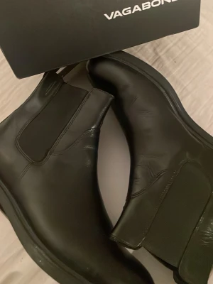 Svarta boots  - Stilrena svarta Chelsea boots från Vagabond i slätt läder. Klassisk siluett med elastiska resårpaneler på sidorna och låg klack. Perfekta för dig som vill ha en tidlös och trendig look till hösten och vintern.