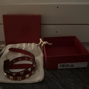 Rött valentino armband med nitar - Ett rött valentino armband som passar till allt, som gör en outfit stilrent. Den är i mycket bra skick, användt några gånger, har gjort ett extra hål men inget man tänker på när man har på sig de. Har du några frågor så tveka inte på att höra av dig till mig, priset kan diskuteras. 