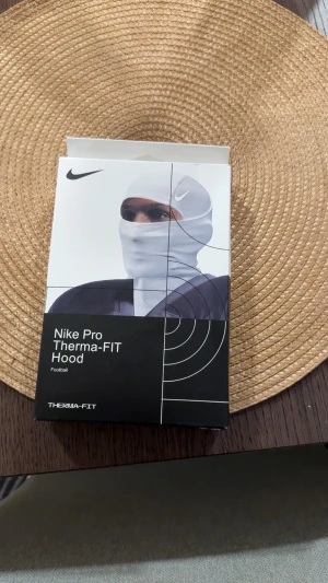Nike ski mask  - Nike Pro Therma-FIT Hood är en sportig och funktionell huva i svart, designad för att hålla dig varm under träning eller utomhusaktiviteter. Tillverkad i Therma-FIT-material som ger extra värme och komfort. Perfekt för fotboll och andra sporter.