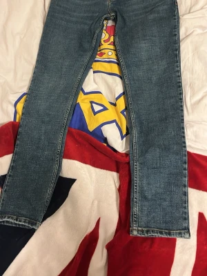 Blå Hugo boss jeans i klassisk modell som är aldrig använt - Säljer ett par blå jeans med rak passform och klassisk denimlook. Jeansen har en enkel design utan synliga loggor eller detaljer, och är tillverkade i ett traditionellt denimtyg. Perfekta för en avslappnad och stilren vardagsstil. nypris: 1200 mitt pris 750kr.  Passar nån som är 165 men lite långa i benen. Har aldrig använt ute då den var för liten mär jag köpte. Kan gå ner i pris vid snabb affär