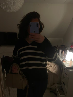 Svart tröja med vita ränder - Snygg svart tröja med breda vita horisontella ränder. Tröjan har rund halsringning och långa ärmar, perfekt för en avslappnad och trendig look. Passar bra till jeans eller kjol.