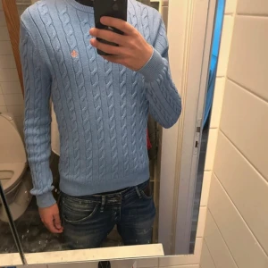 Morris - Snygg ljusblå stickad tröja från Morris  med klassiskt kabelmönster och rund hals. Inga skador, storlek M