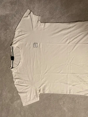 Vit t-shirt från BOSS - Snygg vit t-shirt från BOSS med liten logotyp på bröstet. Klassisk passform och rund halsringning. Tillverkad i mjuk bomull som känns skön mot huden. Perfekt basplagg för en clean och stilren look.