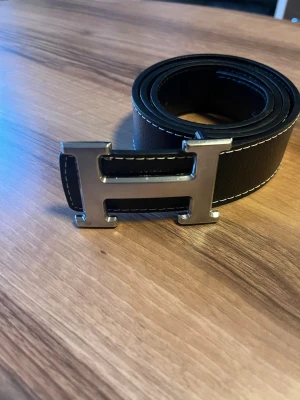 H spänne bälte - Längd 105 cm svart lite använd syns inte när man har den på sig. Silver spänne