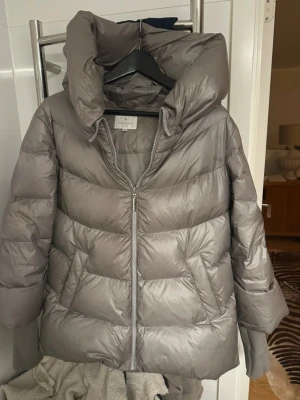 Grå pufferjacka från Intown - Säljer en grå pufferjacka med stor, hög krage och dragkedja framtill. Jackan har quiltad design och breda ribbade muddar vid ärmslut. Perfekt för kalla vinterdagar och riktigt snygg att styla med jeans eller leggings. 