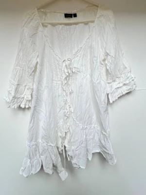 Vit blus med volanger och knytband - Söt vit blus från Lindex i storlek 44, med volangdetaljer, trekvarts armar och 3st knytband framtill☀️ -Volang på ärmarna och nedtill -100% bomull