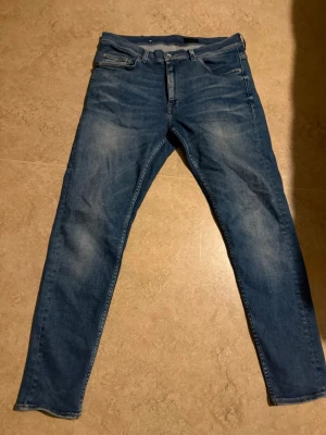 Blå slim jeans med klassisk passform - Säljer ett par tiger of sweden jeans i storleken 34/32. Ett par sköna jeans i rätt så ny skick knappt änvända. Köptes för 1500kr, säljer de då jag tycker dem ä lite stor och de därför jag knappt använt dem.