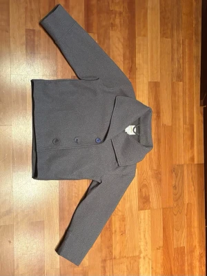 Grå kappa med hög krage från Gina Tricot - Jättefin kappa från Gina tricot i storlek S. Passar perfekt till sen vinter/vår när det börjar bli lite varmare. Kragen är hög men kan göras till låg.