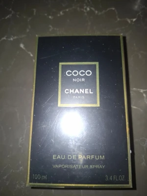 Coco Noir Eau de Parfum från Chanel - Coco Noir Eau de Parfum från Chanel i elegant svart och guld förpackning. Flaskan rymmer 100 ml och har en lyxig, modern design med tydliga guldkanter och klassisk Chanel-logga. En ikonisk doft som utstrålar exklusivitet och stil. Köpt på Vinted