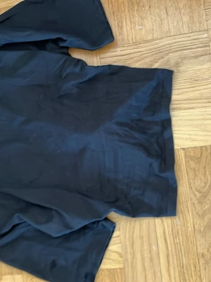 Svart t-shirt med knyt baktill - Snygg svart t-shirt med knyt baktill. Toppen har korta ärmar och är perfekt att styla med jeans.