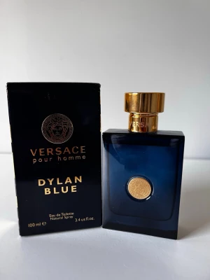 Versace Dylan Blue Pour Homme EdT 100ml - Versace Dylan Blue Pour Homme Eau de Toilette i en elegant mörkblå glasflaska med gulddetaljer och Versace-logga. Flaskan rymmer 100 ml och har en lyxig, maskulin design med guldfärgat spruthuvud och lock. Kommer i originalförpackning.