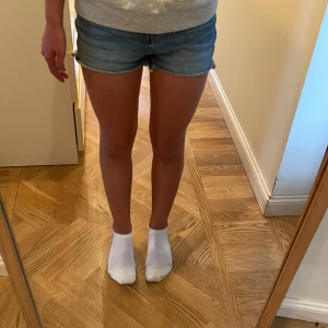 Blå jeansshorts från Lindex - Snygga blå jeansshorts från Lindex med rätt hög midja. Perfekta till sommaren och lätta att matcha med allt. Sköna och fina shorts i denim som ger en avslappnad vibe.