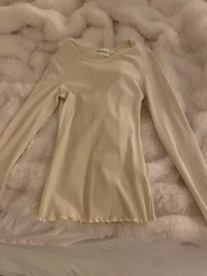 Ribbad krämvit långärmad topp Carin Wester - Säljer en stilren vit ribbad långärmad topp från Carin Wester i storlek XS. Toppen har en rund halsringning och är tillverkad i ett mjukt, stretchigt material som sitter snyggt på kroppen. Perfekt att matcha med jeans eller kjol.