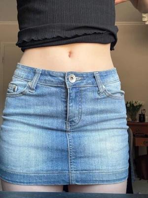 Blå lågmidjad jeanskjol  - Säljer en klassisk blå jeanskjol från Miss Anna. Kjolen är kort, har fem fickor, bälteshällor och stängs med knapp och dragkedja framtill. Perfekt till sommaren och enkel att matcha med olika toppar. Står ingen lapp men jag tycker det är som en xs. 