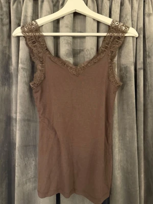 Pieces brunt spets linne - Ett brunt spetslinne från Pieces i storlek XS. Super fint för sig själv eller under en kofta samt blus. Använt två gånger så nästan som nytt💗