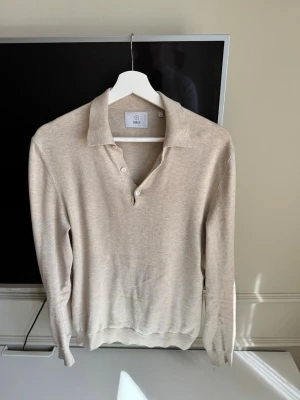 Beige långärmad tröja från Bläck - Stilren beige långärmad tröja från Bläck                   Perfekt för en clean och avslappnad look.