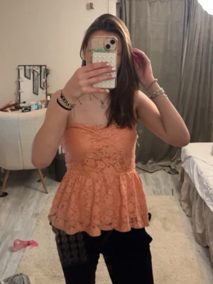 Rosa spets tubtopp - Söt rosa tubtopp med volangkant och spetsdetaljer. Toppen är axelbandslös och har en figurnära passform upptill med utsvängd nederdel. Perfekt för dig som vill ha en feminin och trendig look.