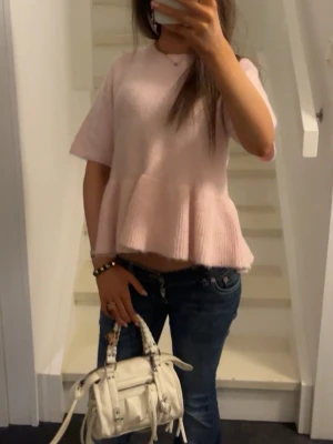 Ljusrosa volangstickad topp - Supersöt ljusrosa topp med volangkant och korta ärmar. Toppen är stickad och har en lös passform som ger en avslappnad men ändå feminin look. Perfekt att styla med jeans eller kjol för en trendig outfit.