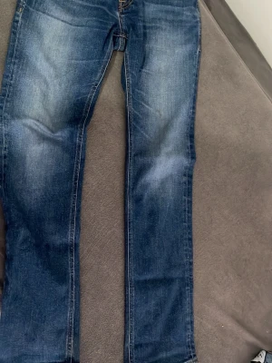 Blå jeans från Jack & Jones - Snygga blå jeans från Jack & Jones med klassisk femficksmodell och kontrastsömmar. Jeansen har en rak passform och slitningar på låren för en cool, avslappnad look. Tillverkade i slitstarkt denimtyg som passar perfekt till vardagsstilen.