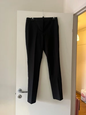 Svarta kostymbyxor med rak passform - Snygga svarta kostymbyxor med rak passform och pressveck. Byxorna har en klassisk midja och smala ben, perfekta till en stilren look. 