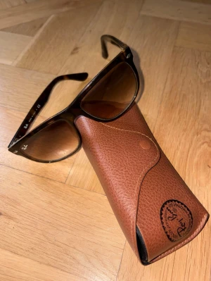 Ray-Ban Boyfriends - Snygga solglasögon från Ray-Ban i brun transparent plast med klassisk form. Tillverkade i Italien och passar perfekt för dig som vill ha en tidlös accessoar med stilren design. Det är den mindre storleken. Lite svårare att få tag i.