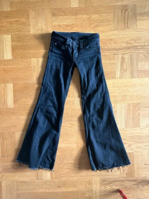 Svarta utsvängda jeans med rå kant - Säljer ett par cheap Monday jeans, low waist! Jag har klippt dom så att dom kappas perfekt för er som är 160cm!! Jätte fint skick med har använt dom men inom spannet på 6månader. Storlek 24/30.