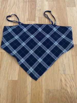 Rutig svart och vit linnetopp - Trendig linnetopp med smala axelband i svart och vitt rutigt mönster. Toppen har en bandanaformad nederkant och smockad rygg för extra komfort. Perfekt för att skapa en cool och avslappnad stil.