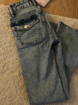 Ljusblåa jeans med knappfickor  - Kommer inte till användning eftersom dom är för små för mig! Jag är 164 cm. Och storleken är XSS så skulle rekommendera för nån som är 160- och under🥰